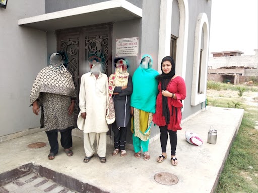Arif Masih and his family stand in front of RAMs shelter house. Their faces are blurred.